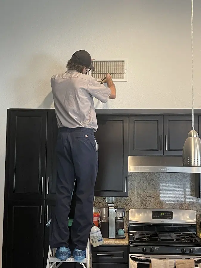 Technician inspecting an air vent during HVAC service in Lombard